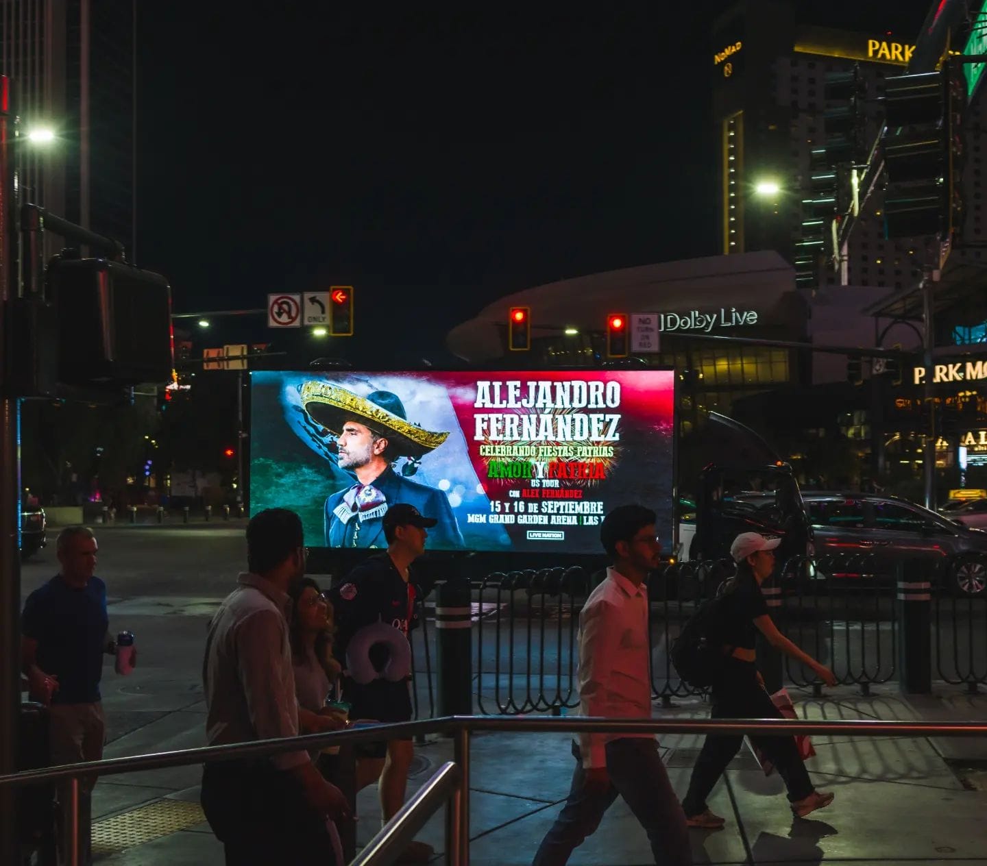 People near illuminated billboard at night in city.