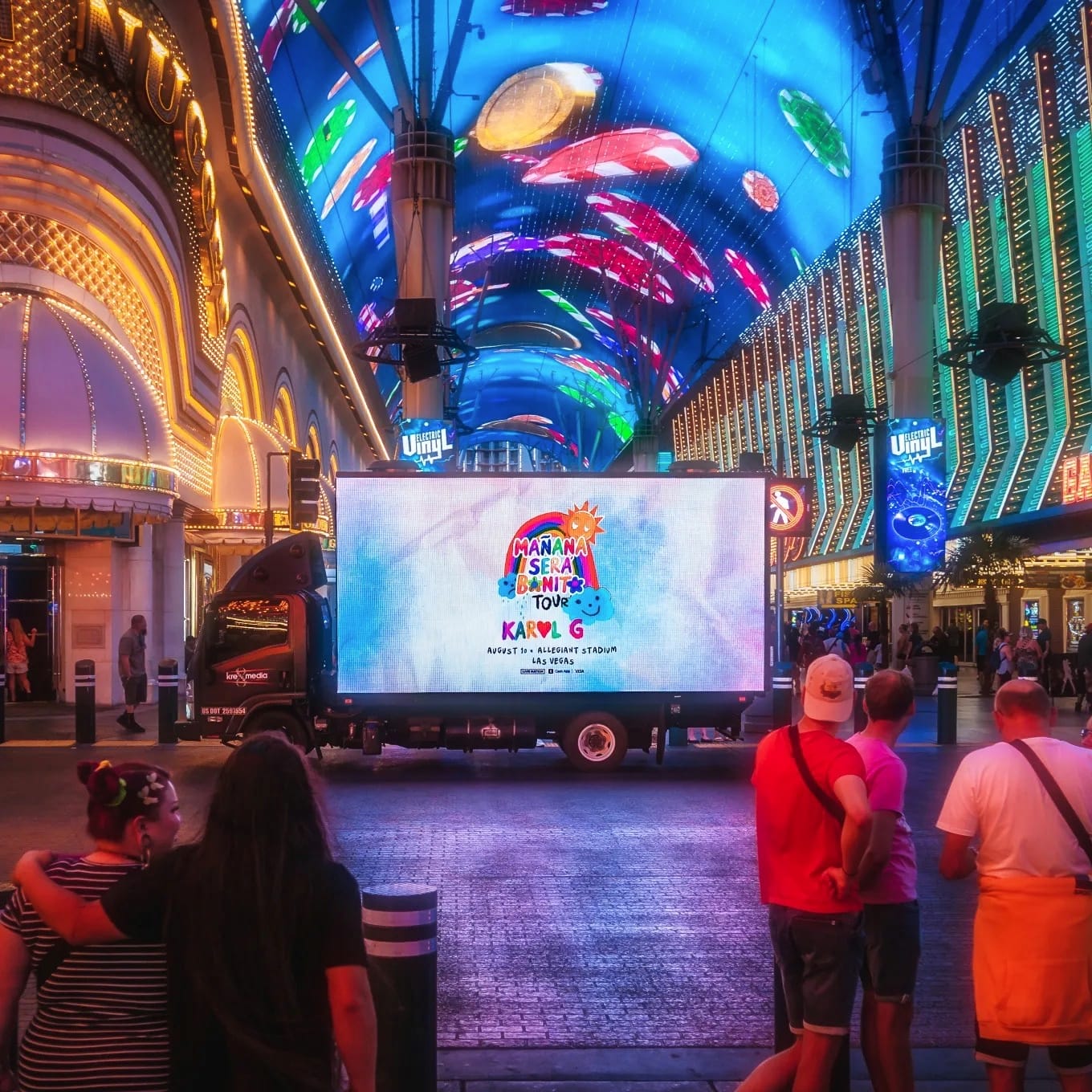 Vibrant LED-lit street with advertising truck and pedestrians.