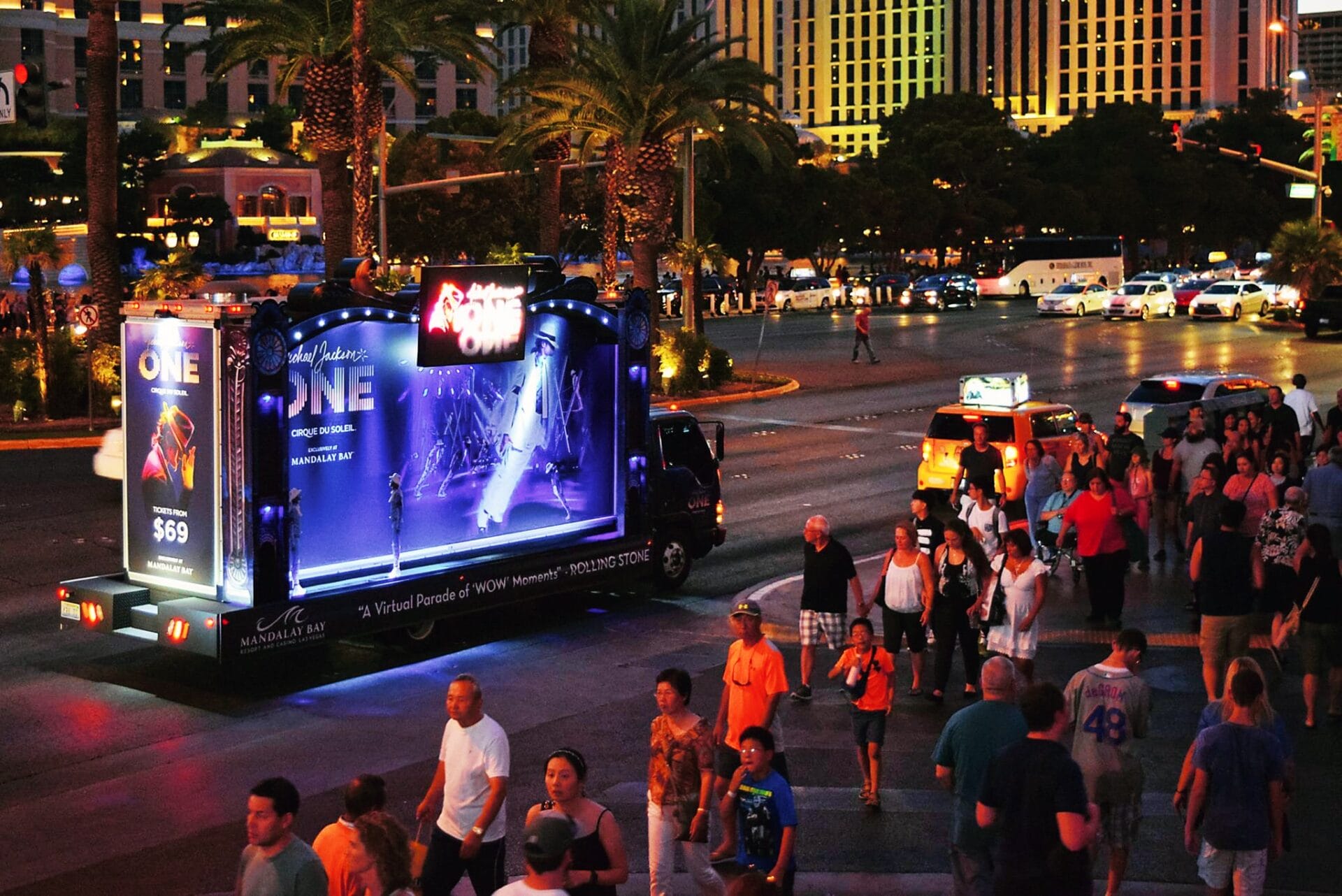 Crowded intersection with mobile billboard at twilight.