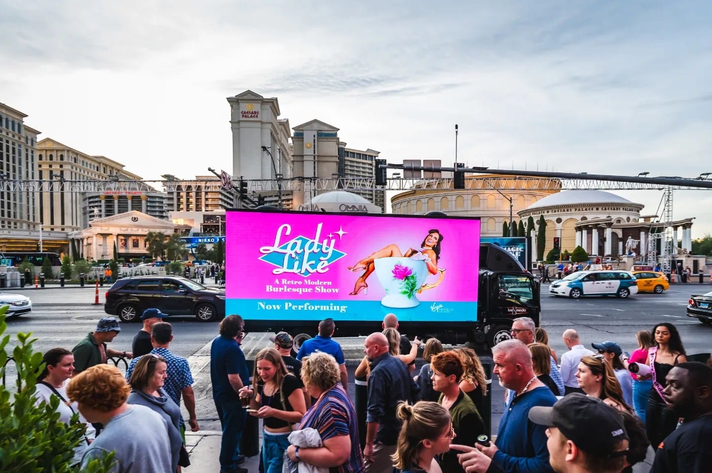Crowd near billboard advertising Las Vegas show.