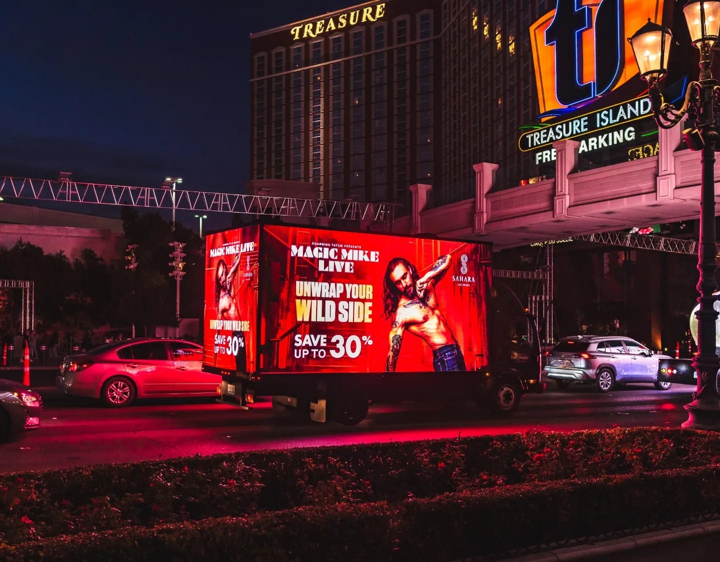 Illuminated Magic Mike billboard truck at night by casino.