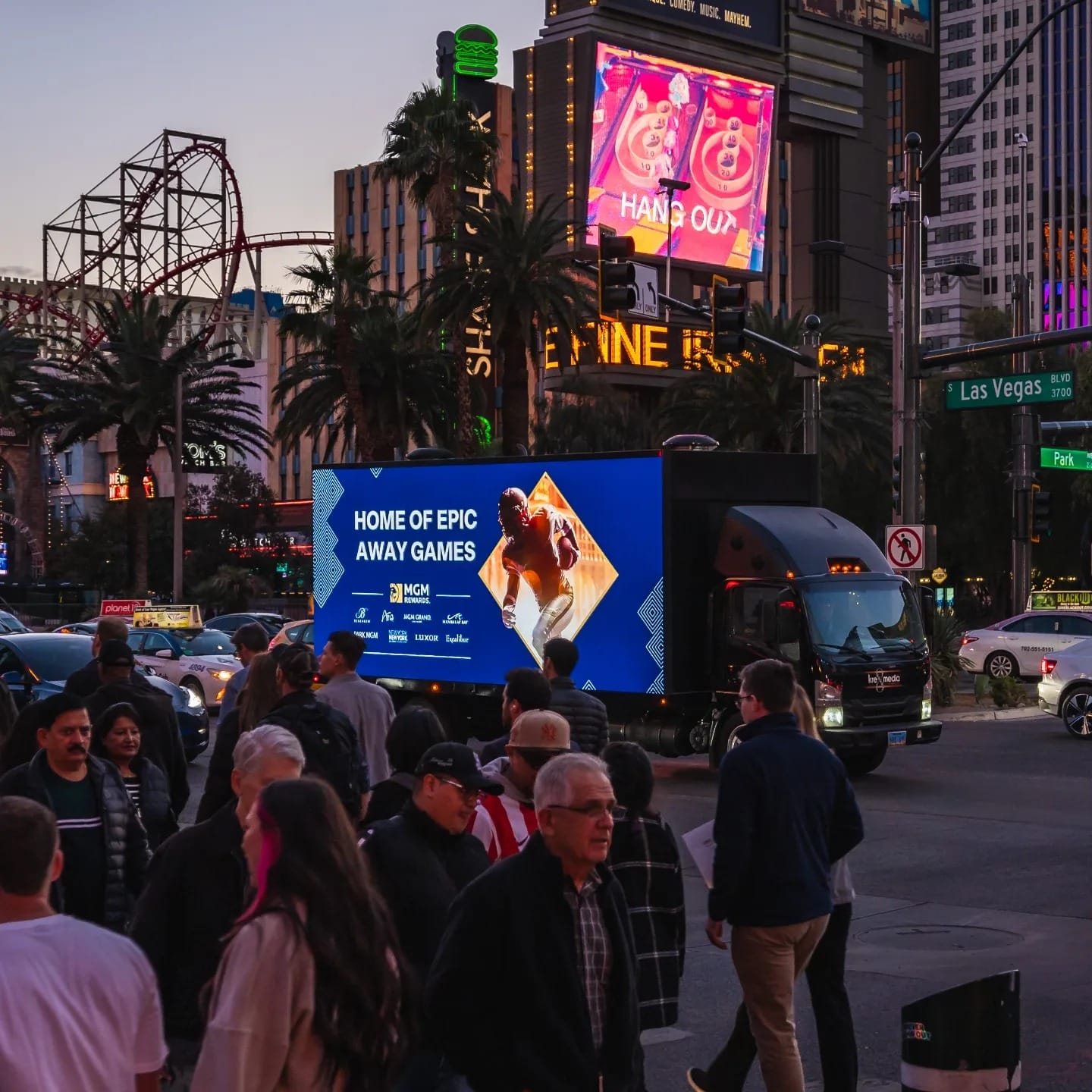 Crowd walking near illuminated billboards in Las Vegas.