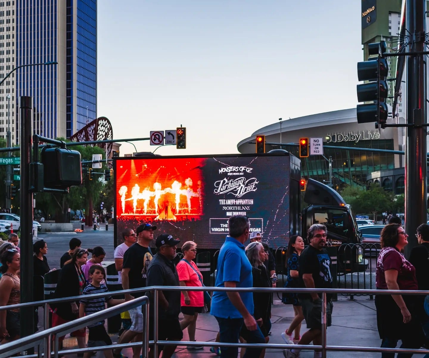Crowd near billboard in busy city at twilight.