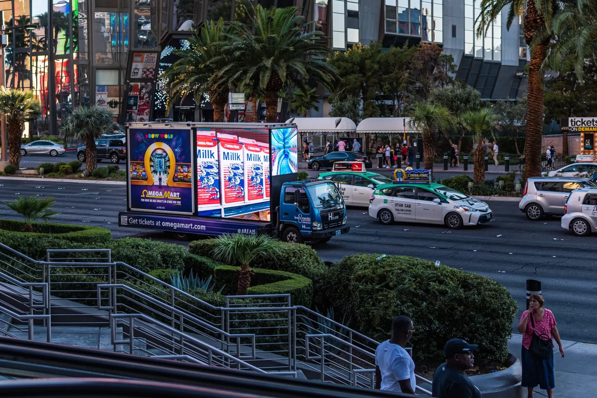 Busy city street with digital advertising and pedestrians.