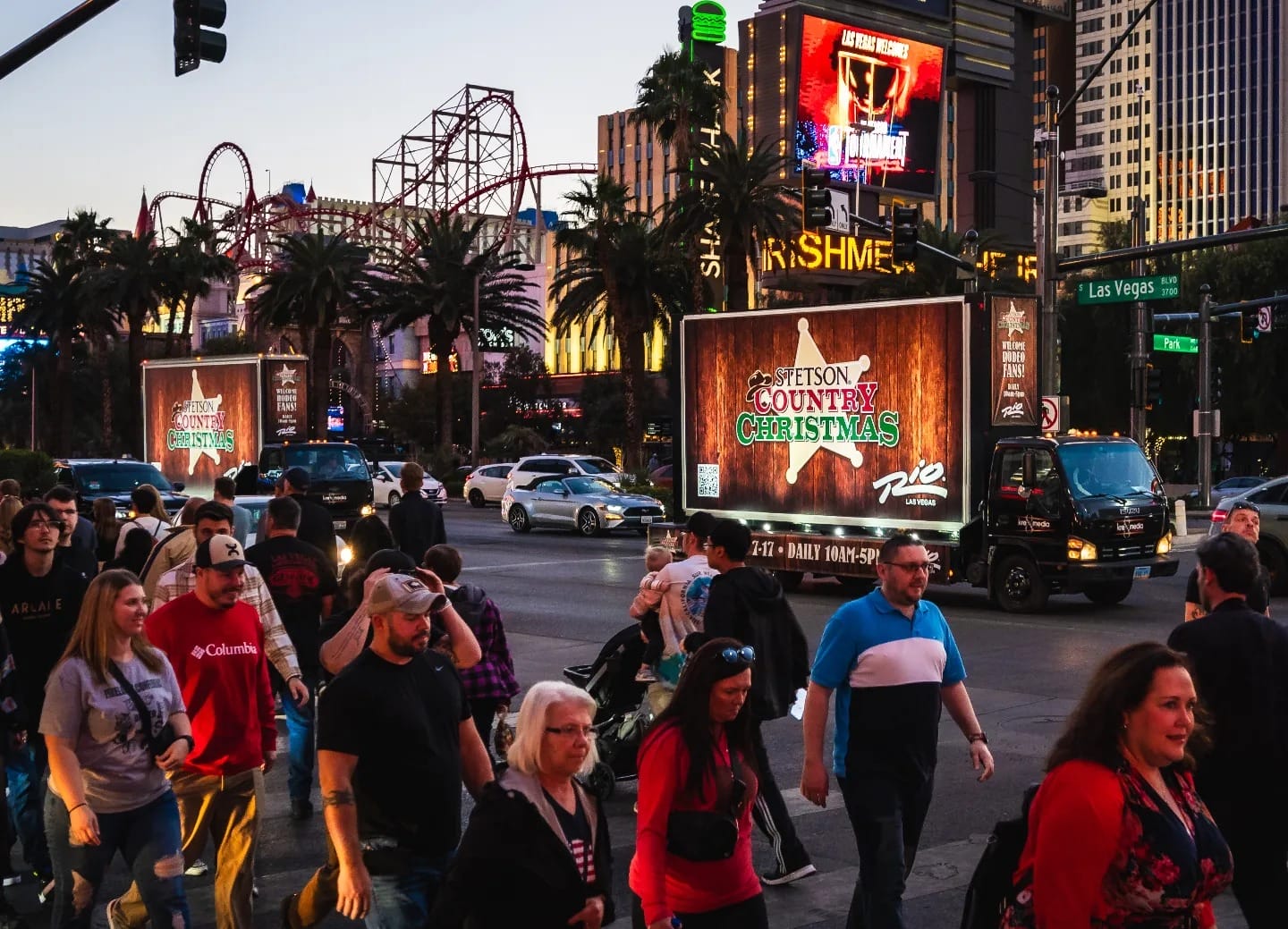 Crowded Las Vegas street with neon signs at dusk.