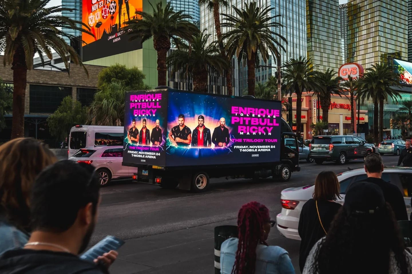 Billboard truck advertising concert on city street.