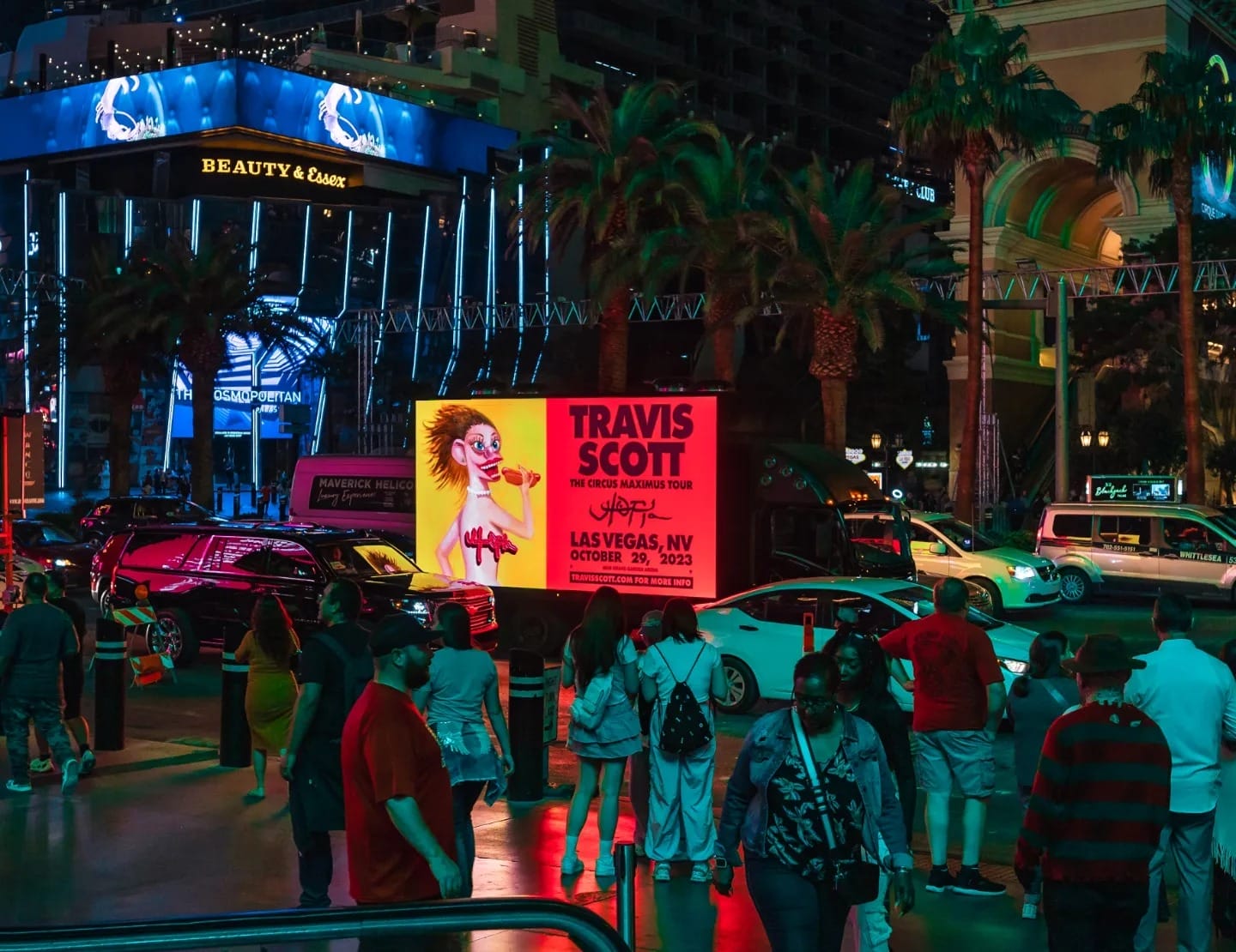 Crowded Las Vegas street at night with illuminated ads.