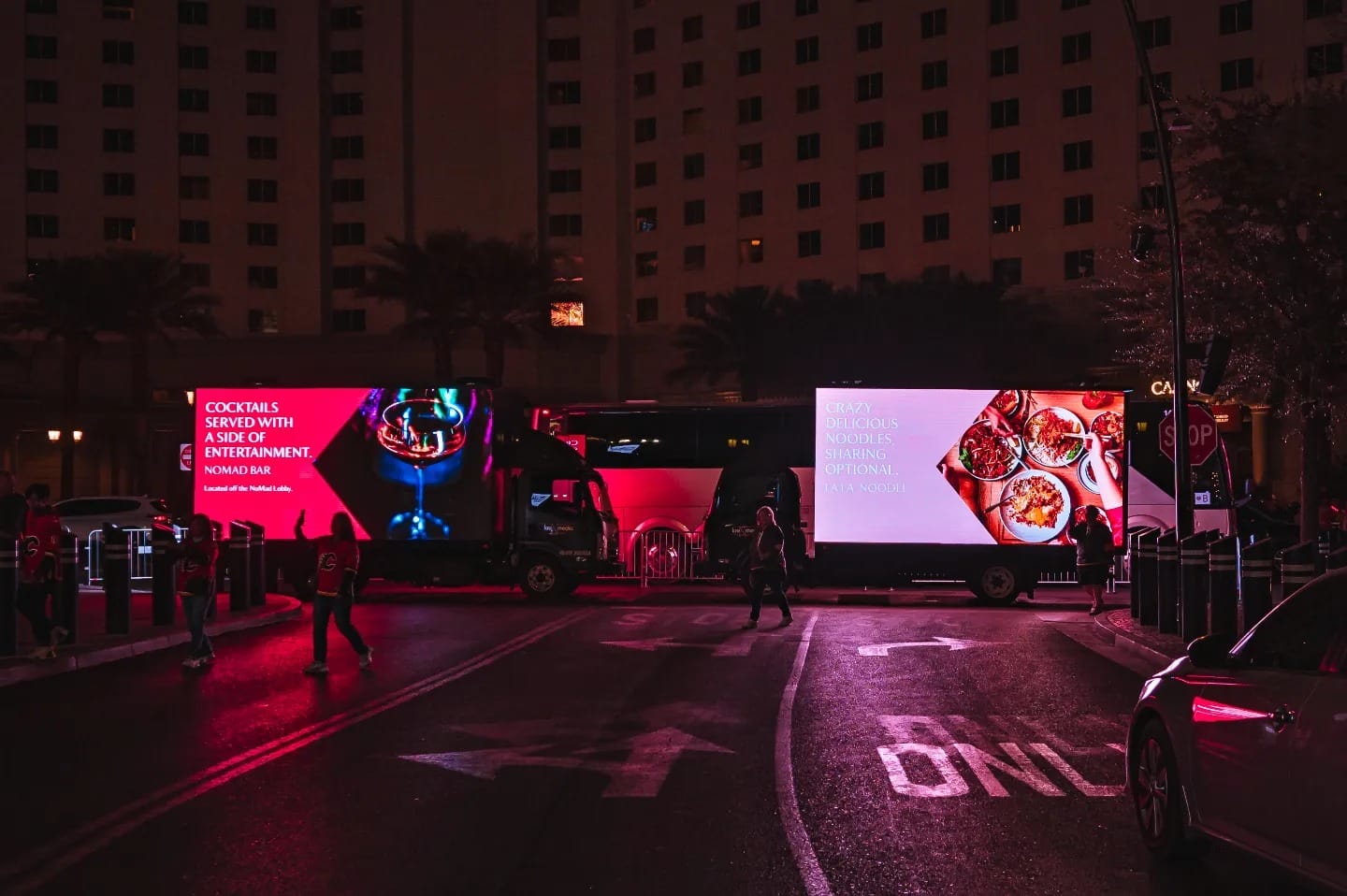 Illuminated food truck ads on city street at dusk.