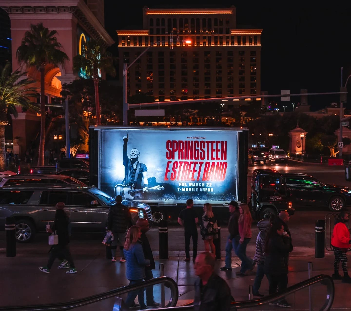 Illuminated billboard advertising a Springsteen concert at night.