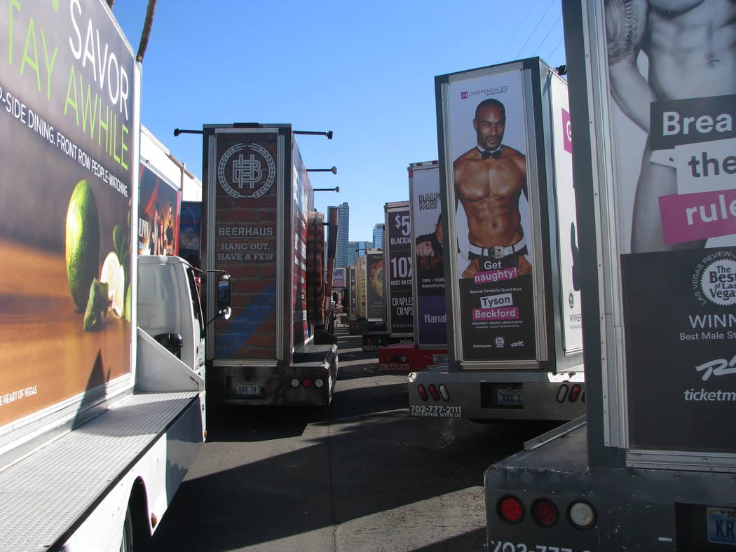 Mobile billboards displaying ads parked on sunny street