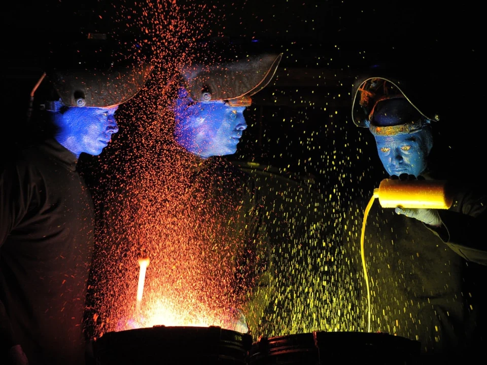 Workers pouring molten metal in dark, vibrant sparks