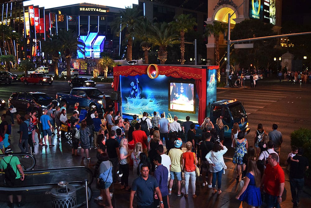 Crowded street with people watching outdoor screen at night