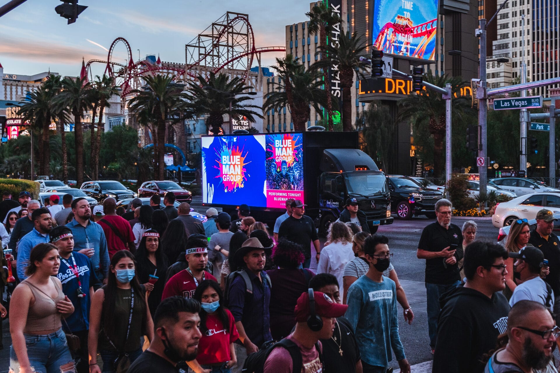 Crowded Las Vegas street with people and digital billboards. Blue Man Group